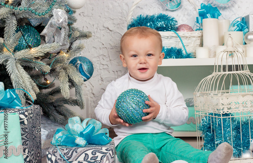 Cute little boy sits near a Christmas tree. Christmas. photo