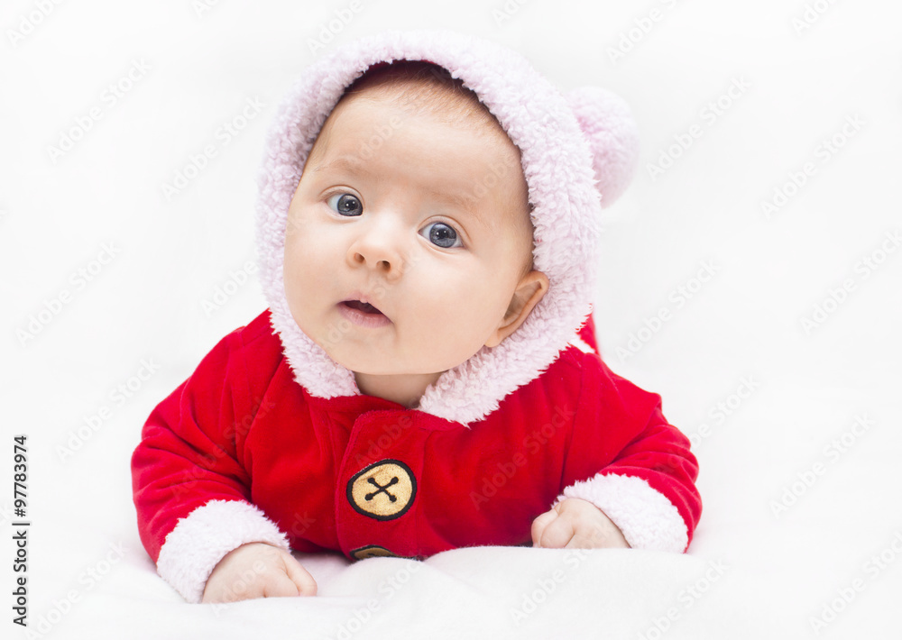 Happy baby lying on tummy wearing a red and white Christmas Santa suit. Happy baby lying on tummy wearing a red and white Christmas Santa suit.
