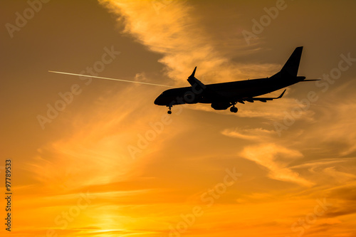 Airplane is landing at the runway during a beautiful sunset.