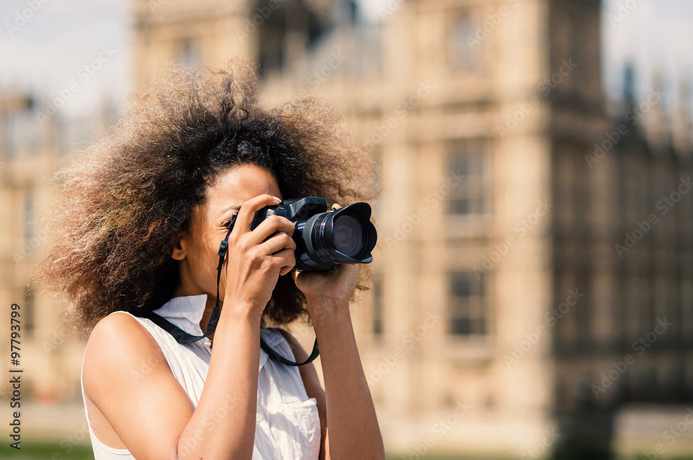 Young woman with camera taking photos in London on Westminster bridge.