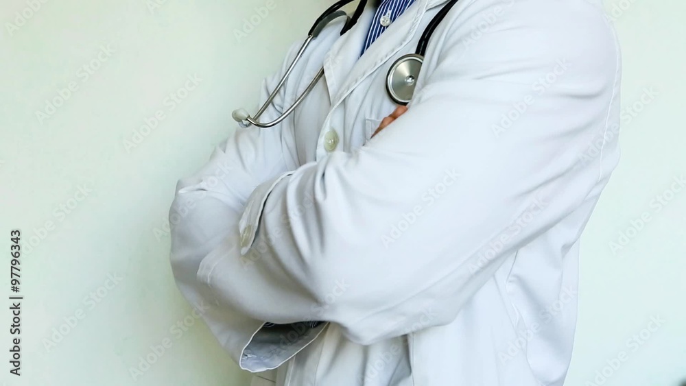 medico con stetoscopio e camice incrocia le braccia