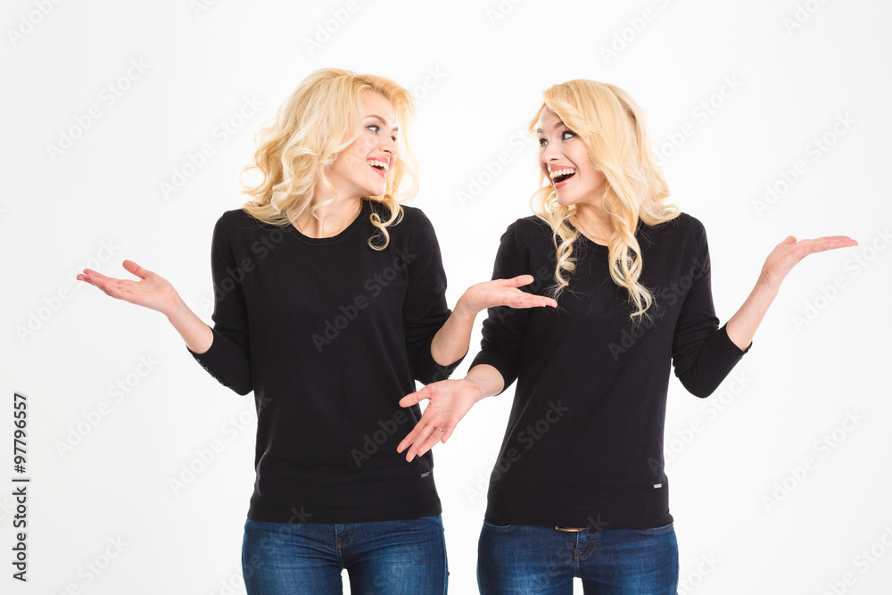 Laughing sisters twins looking at each other and shrugging shoulders Laughing sisters twins looking at each other and shrugging shoulders