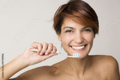 Bella ragazza sorridente mentre si lava i denti photo
