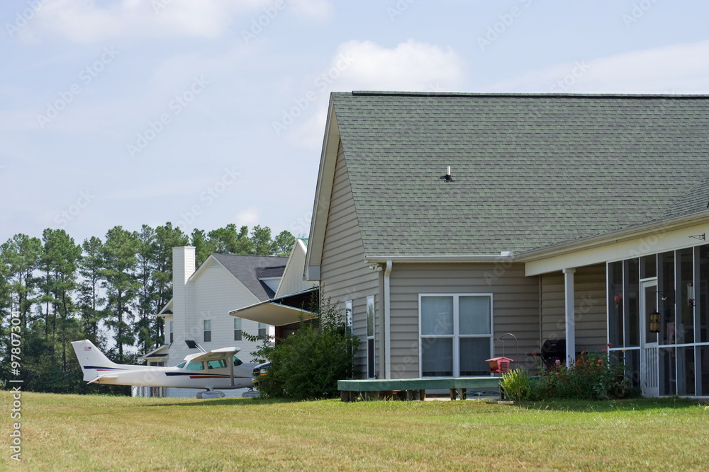 Obraz premium Airplane in Aviation Community – A small aircraft is parked near the hangar, which is next to a home in an aircraft community.