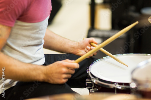 close up of musician with drumsticks playing drums