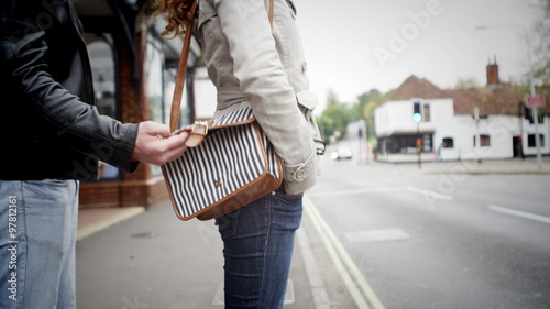  Woman on city street is unaware that her purse has been stolen by pickpocket