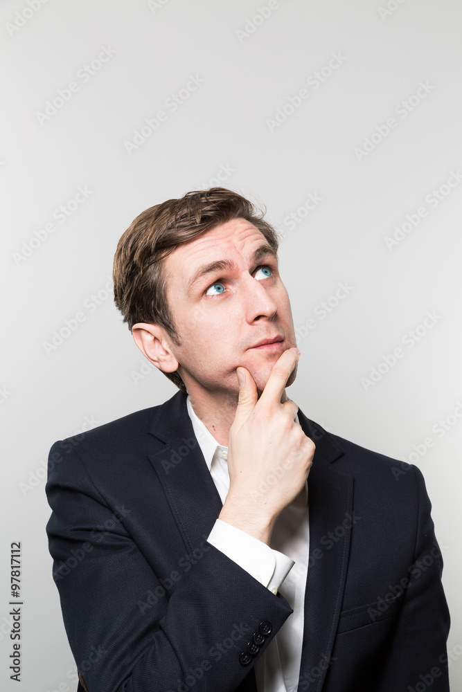 Blond-haired european businessman with a glance stares at the ceiling while in front of a gradient background Blond-haired european businessman with a glance stares at the ceiling while in front of a gradient background