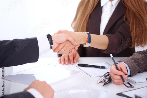 Business handshak sitting at the desk on office background, copy space area at the left upper corner