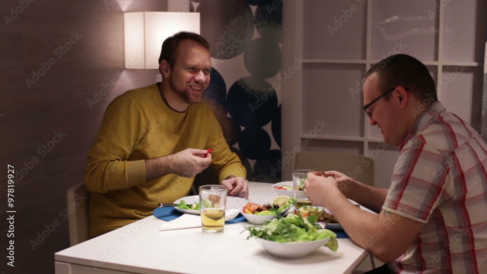 Men sit at table, eating drinking beer and talking Men sit at table, eating drinking beer and talking