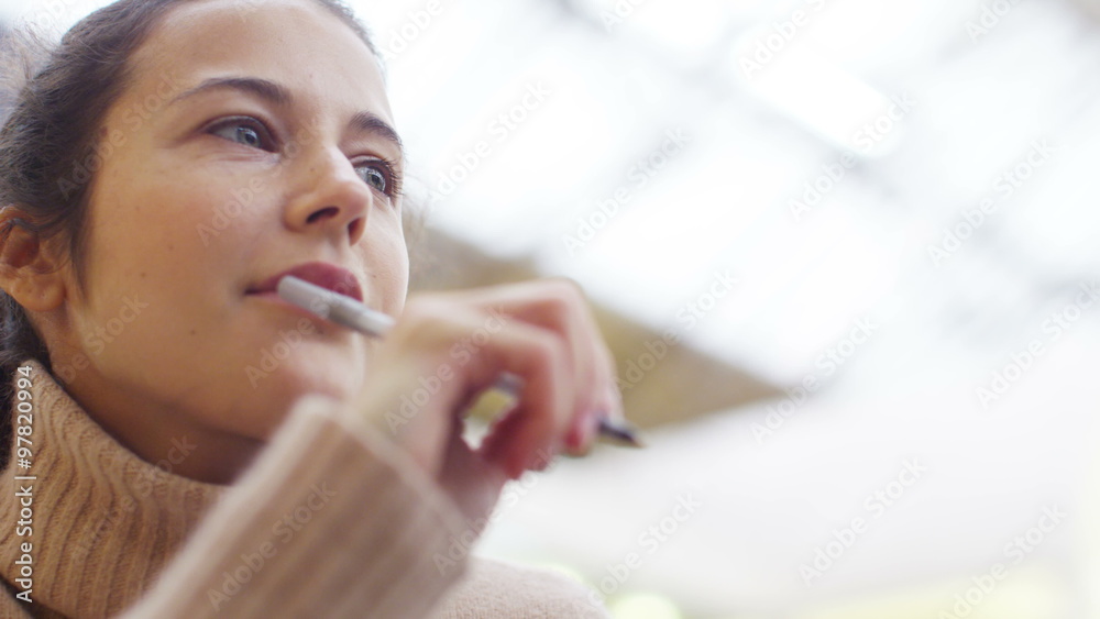  Attractive woman looking thoughtful as she writes in her diary