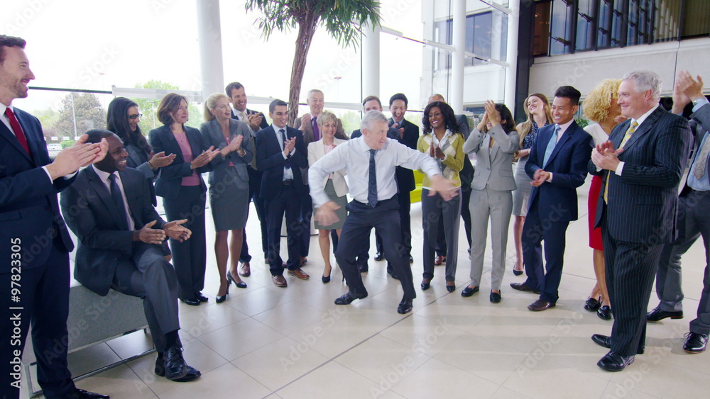 Self confident businessman doing funny dancing to entertain his colleagues Self confident businessman doing funny dancing to entertain his colleagues