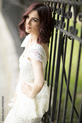 Young woman in white drress by the fence photo