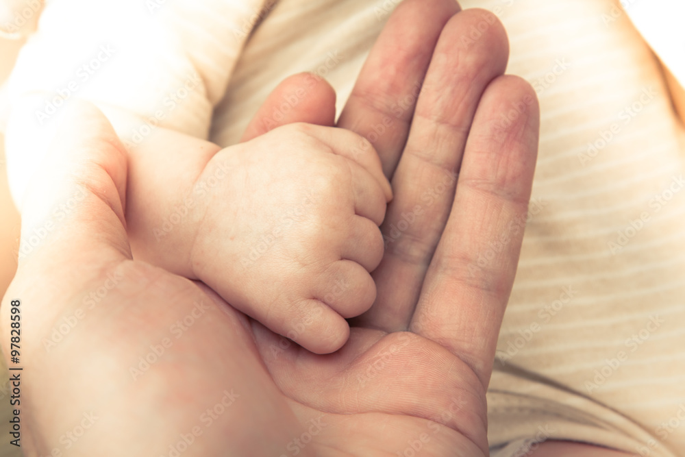 Father holding his newborn baby hand symbolizing love and care. Main focus on baby hand, soft focus on father’s one. Father holding his newborn baby hand symbolizing love and care. Main focus on baby hand, soft focus on father’s one.