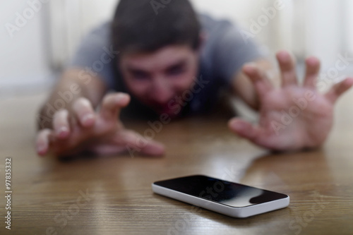 man trying to reach mobile phone creeping on the ground in smart phone and internet addiction concept