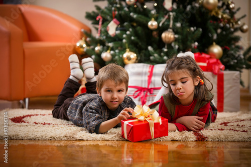 Cute little children opening Christmas presents