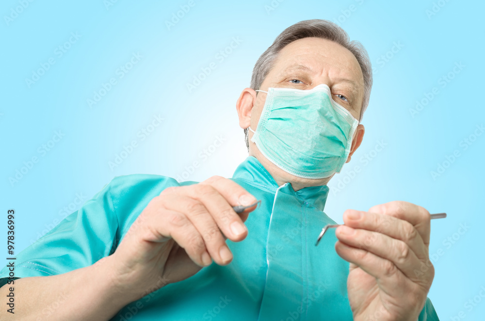 Dentist with a mirror and hook on green background - low angle view Dentist with a mirror and hook on green background - low angle view