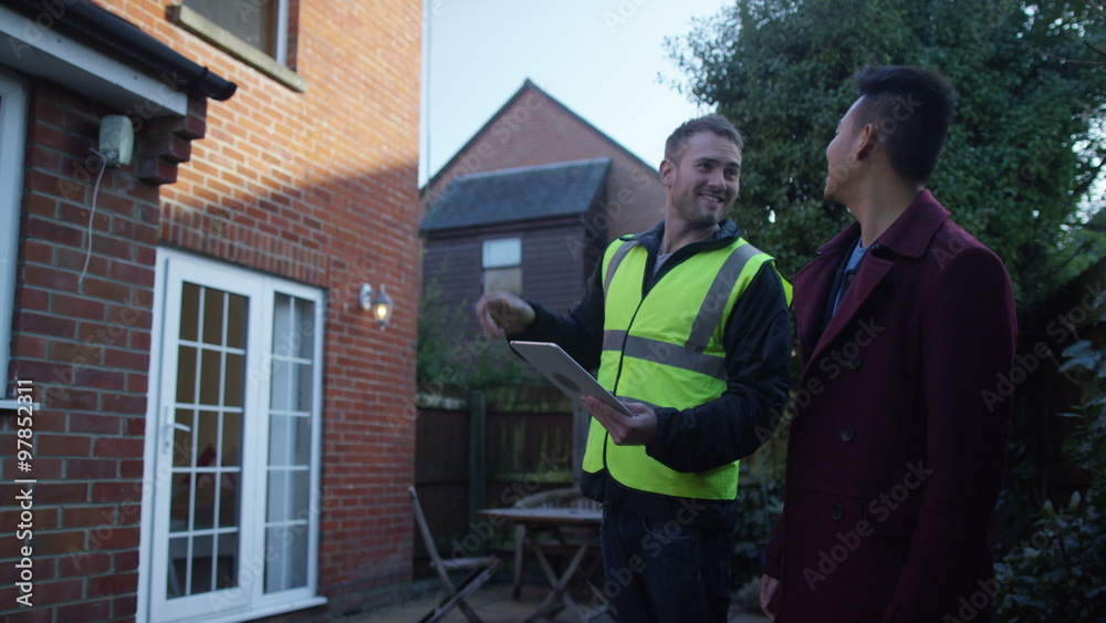 Young man outside his home getting planning advice from builder or architect Young man outside his home getting planning advice from builder or architect