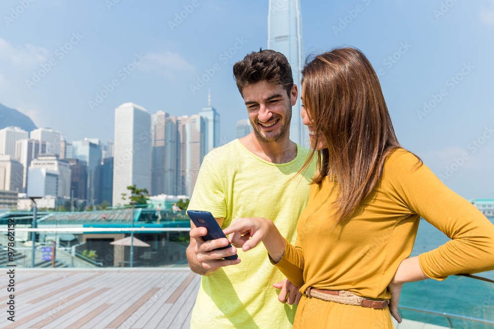 Caucasian couple check the information on cellphone together Caucasian couple check the information on cellphone together