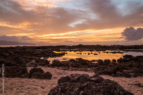 Sunset at Shark's Cove Beach with rocky shore photo