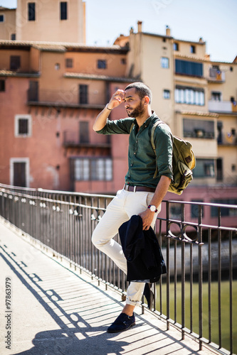 Bearded traveller leaning on parapet and looking away