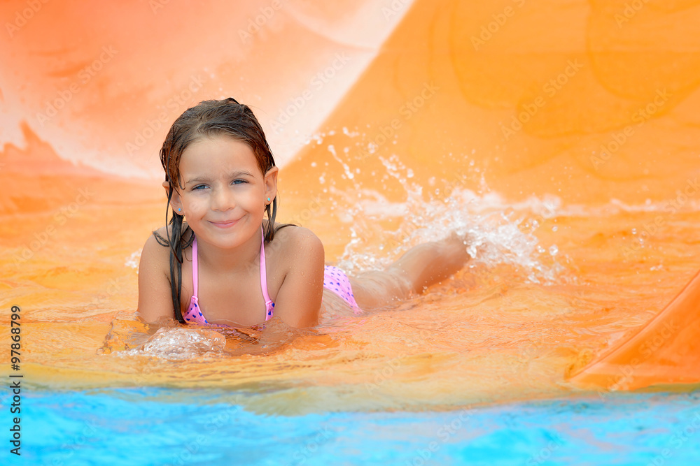 Adorable toddler girl on water slide at aquapark