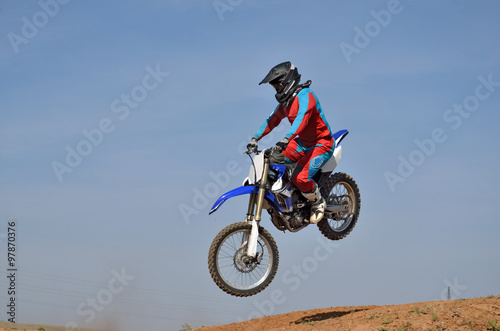 Motocross athlete on a motorcycle motocross jumps down from the hill sideways