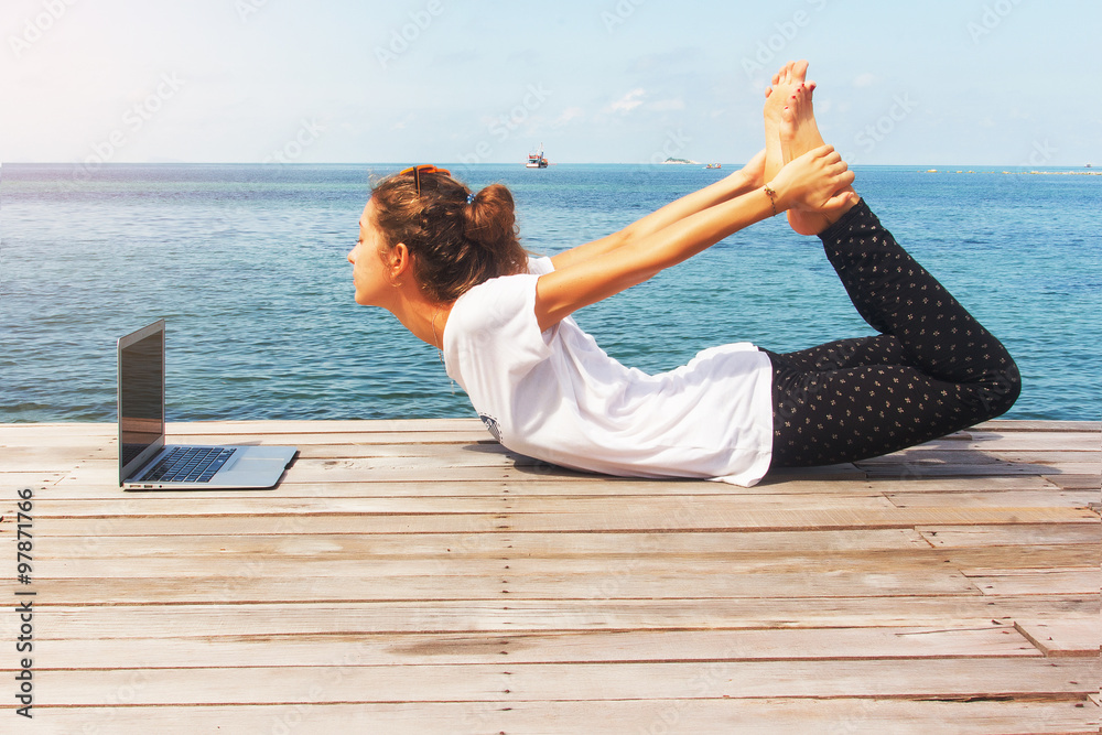 girl has a yoga practice on the wooden floor with laptop