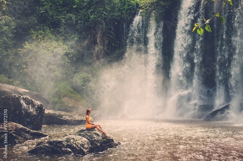 Beautiful woman sitting near waterfall enjoying the sun, Phnom Koulen at Siem Reap, Cambodia photo