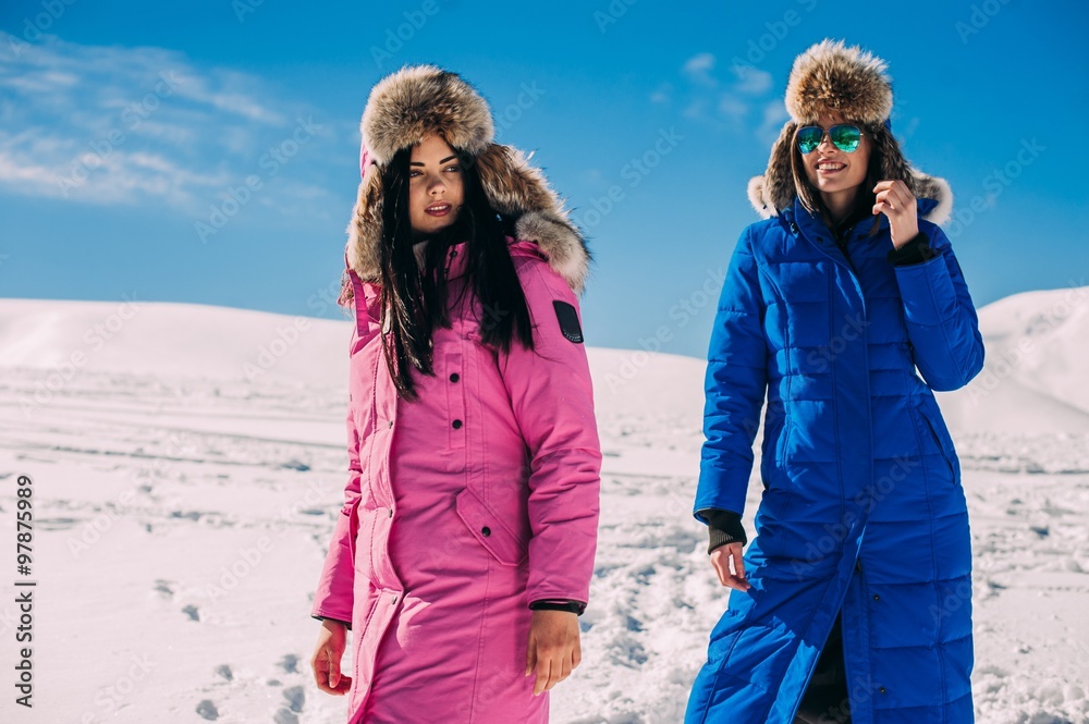 winter, two cheerful young girls having fun in the snow in the m