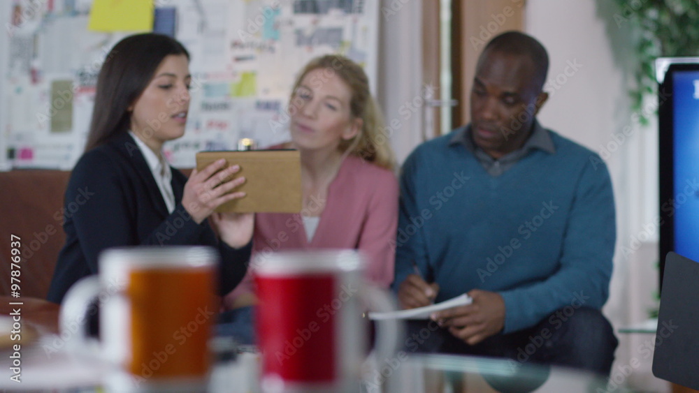 Casual business team in a meeting discussing ideas with computer tablet Casual business team in a meeting discussing ideas with computer tablet