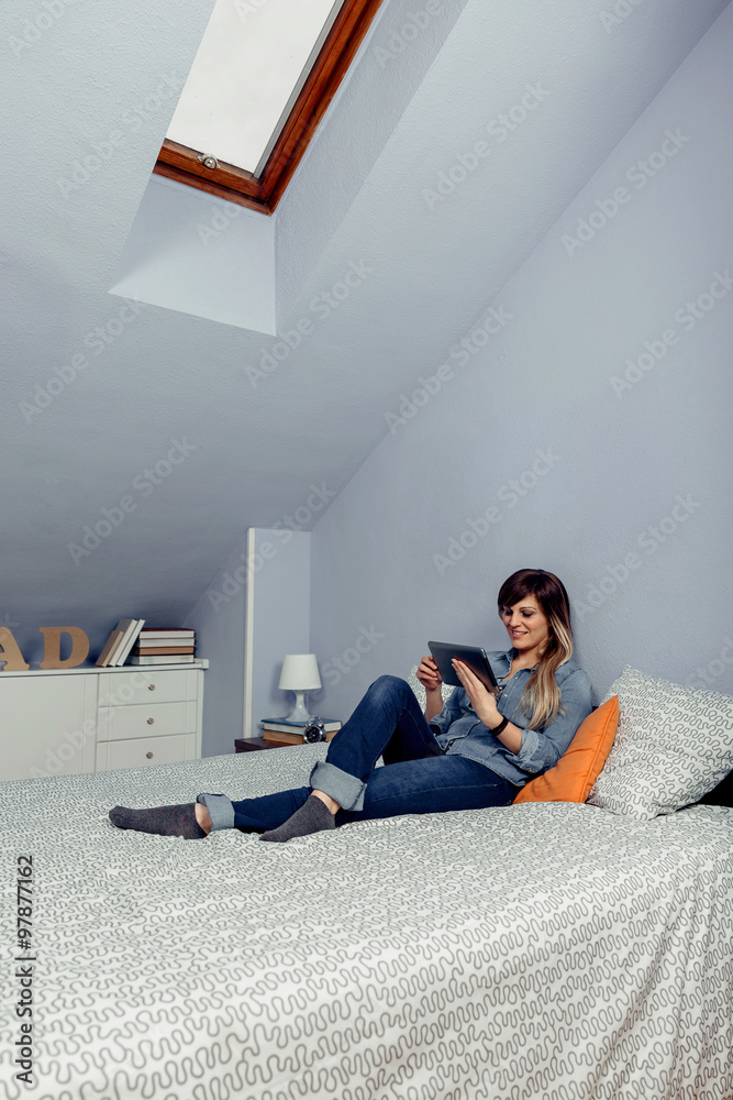 Young beautiful woman looking tablet in a bed
