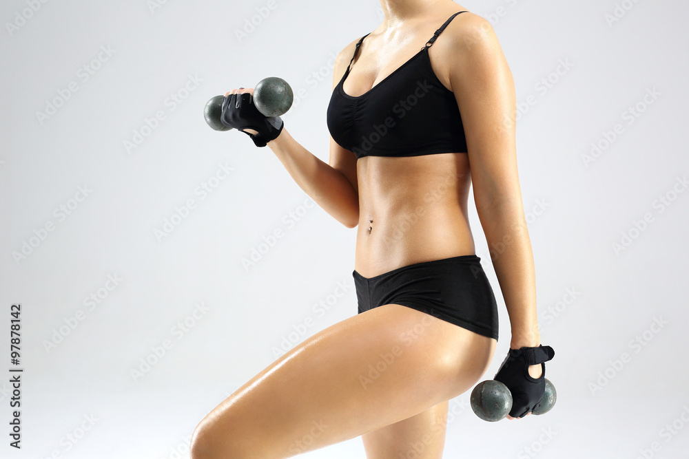 Naklejka premium Sportowa kobieca sylwetka. Kobieta w stroju sportowym podnosi ciężarki.