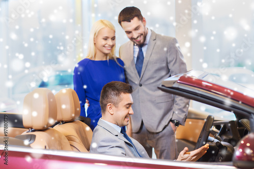 happy couple with car dealer in auto show or salon