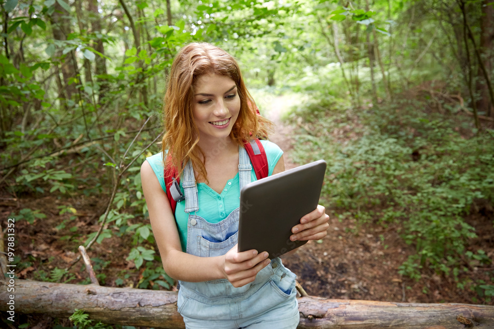 Obraz premium happy woman with backpack and tablet pc in woods