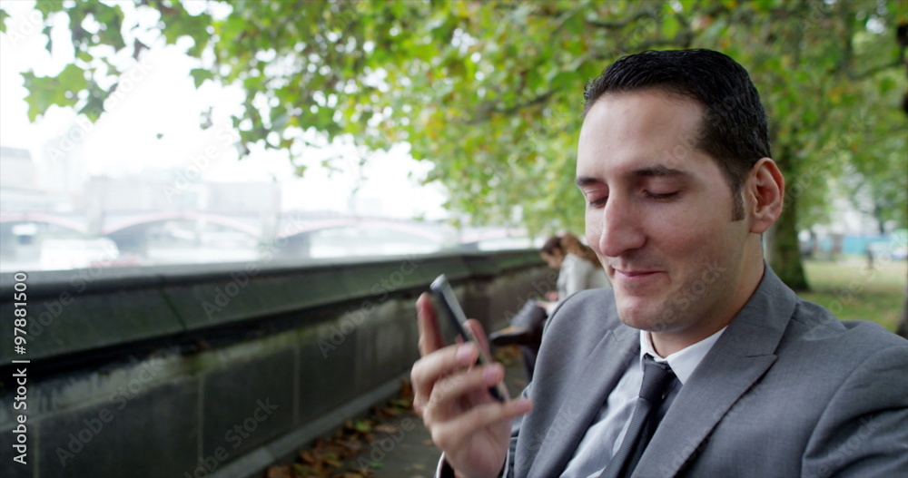 Portrait of young businessman making phone call beside London's River Thames Portrait of young businessman making phone call beside London's River Thames