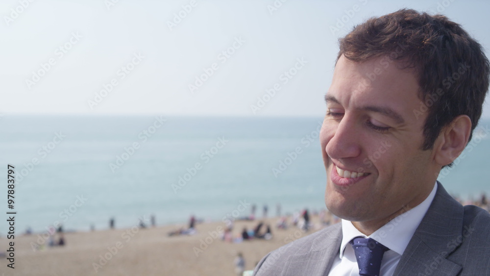 Portrait of smiling businessman talking on mobile phone at the beach. Shot on RED Epic. Portrait of smiling businessman talking on mobile phone at the beach. Shot on RED Epic.