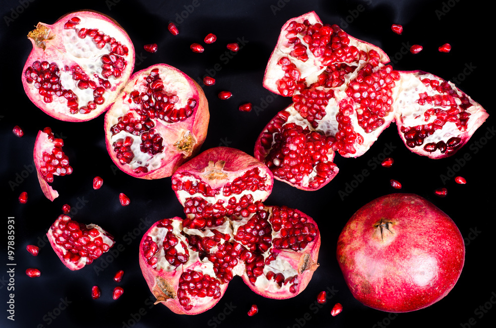 Red juicy pomegranate, whole , half, ripe and broken fruits on black background. Top view. Red juicy pomegranate, whole , half, ripe and broken fruits on black background. Top view.