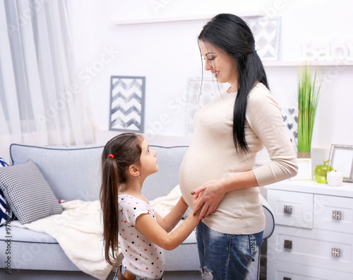 Pregnant mother and daughter in the room