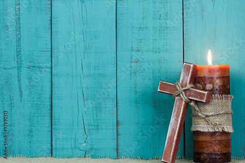 Candle and wooden cross by teal blue wood background photo