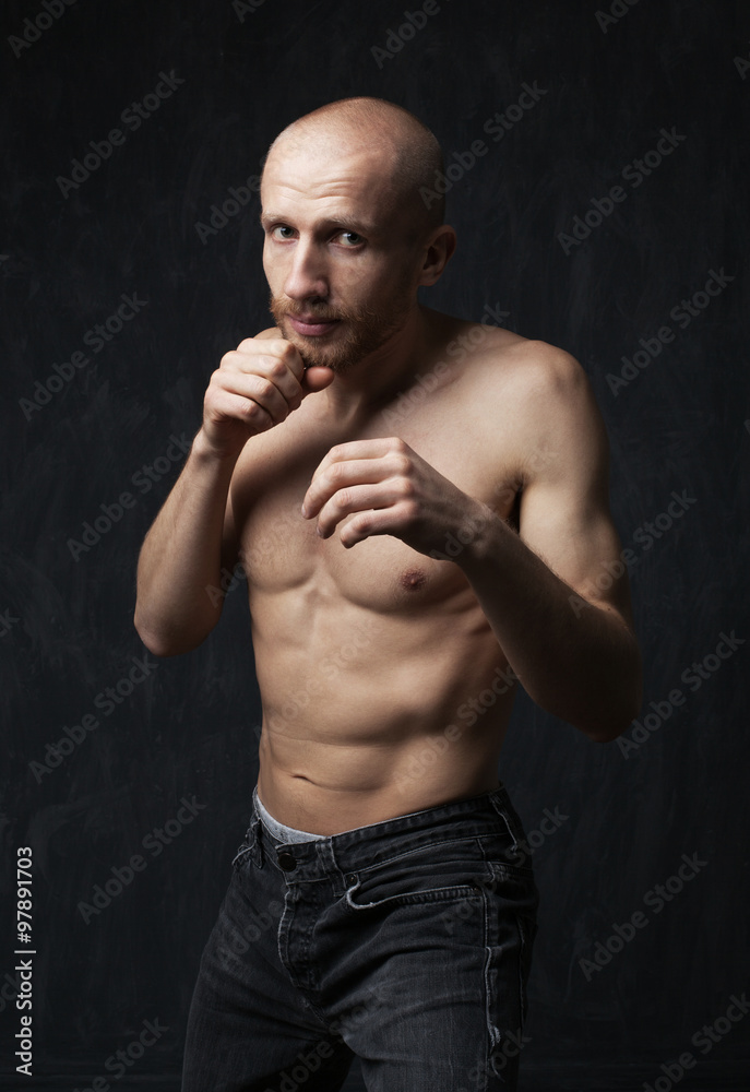 Fighter man with strong abdominal press jab hits his fist on a g