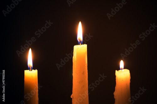 Three burning wax candles on a black background, religion, holid