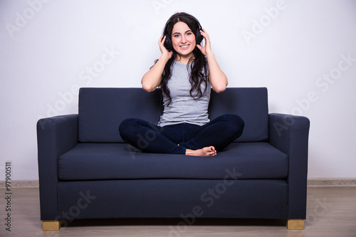 happy woman sitting on sofa and listening music with headphones