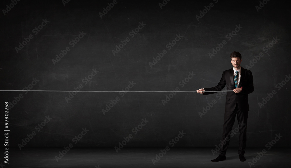 Businessman pulling rope on grey background Businessman pulling rope on grey background