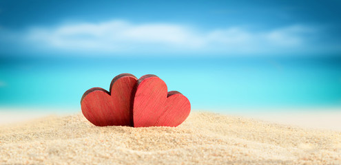 Two wooden hearts on the summer beach