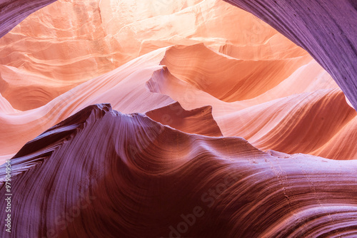 Magnificent nature sun filters into Lower Antelope Canyon Page Arizona USA while the shapes and swirls create and abstract nature image and silica in sandstone reflects some intense colors.