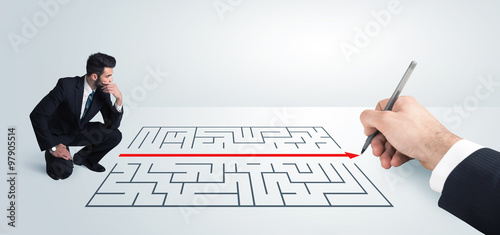 Business man looking at hand drawing solution for maze photo