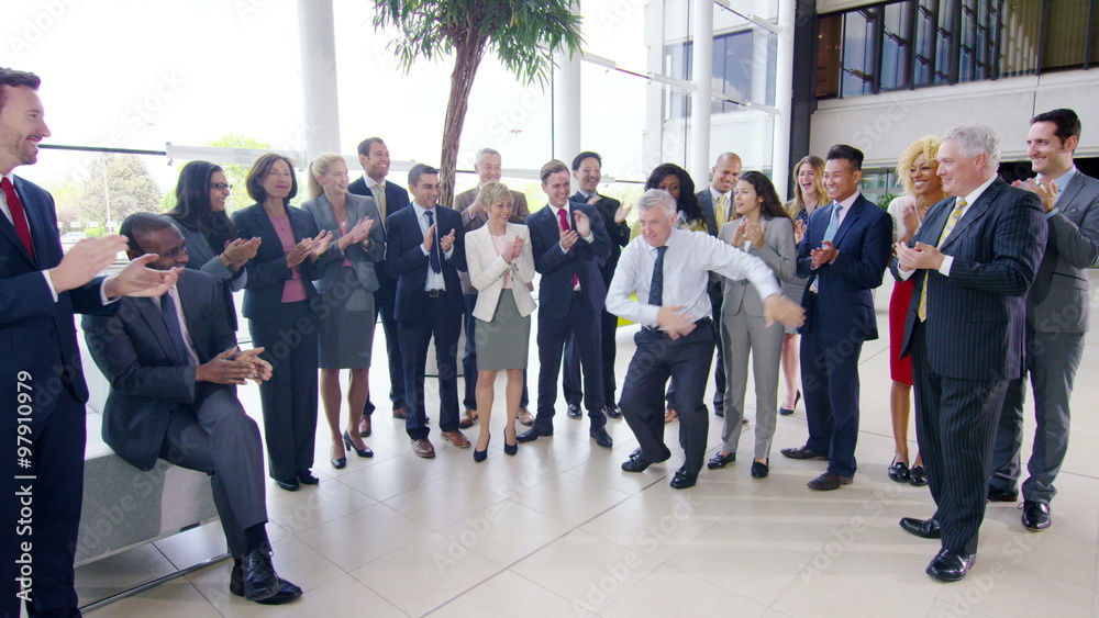 Self confident businessman doing funny dancing to entertain his colleagues Self confident businessman doing funny dancing to entertain his colleagues