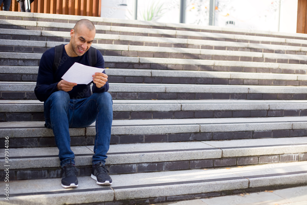 young man sitting on steps reading a letter young man sitting on steps reading a letter