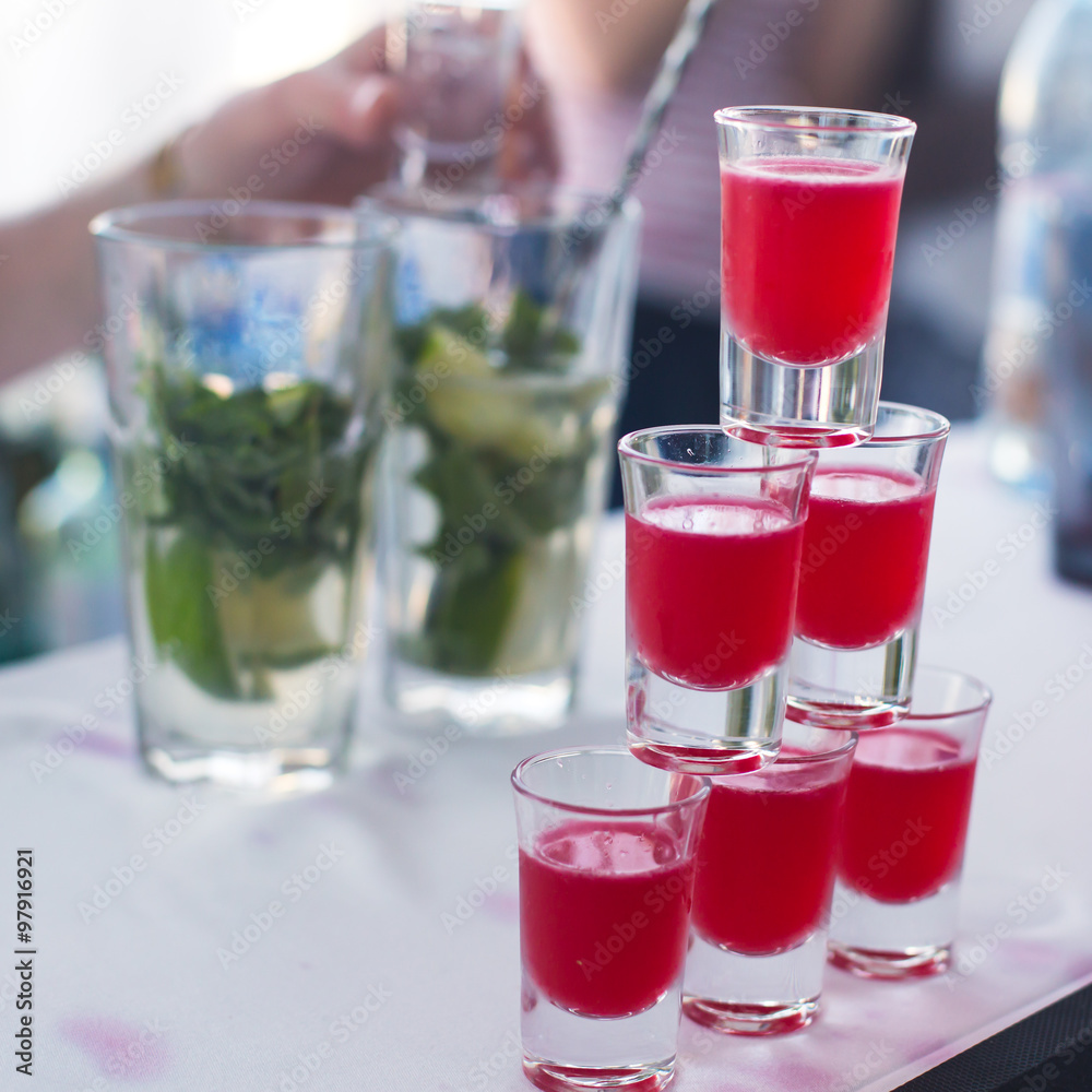 Beautiful row line of different colored alcohol cocktails with mint on a christmas party, martini, vodka with bubbles, wine and others on decorated catering bouquet table on open air event, picture Beautiful row line of different colored alcohol cocktails with mint on a christmas party, martini, vodka with bubbles, wine and others on decorated catering bouquet table on open air event, picture