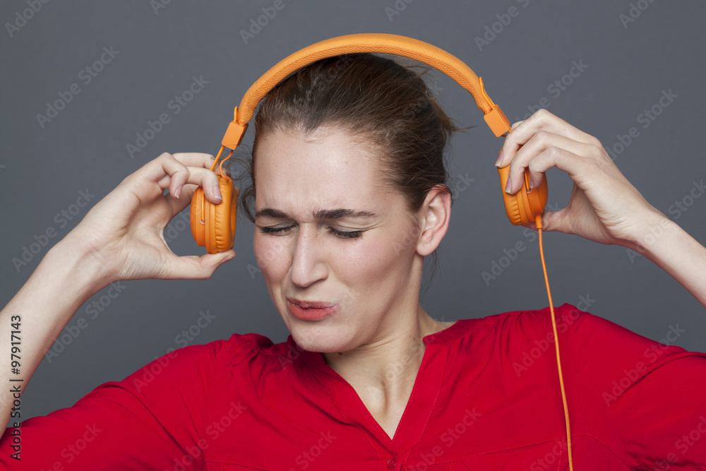 tinnitus headphones concept - stressed out 20s girl listening to loud music  with earphones on,removing her earphones to avoid nightmare,studio shot  Photos | Adobe Stock